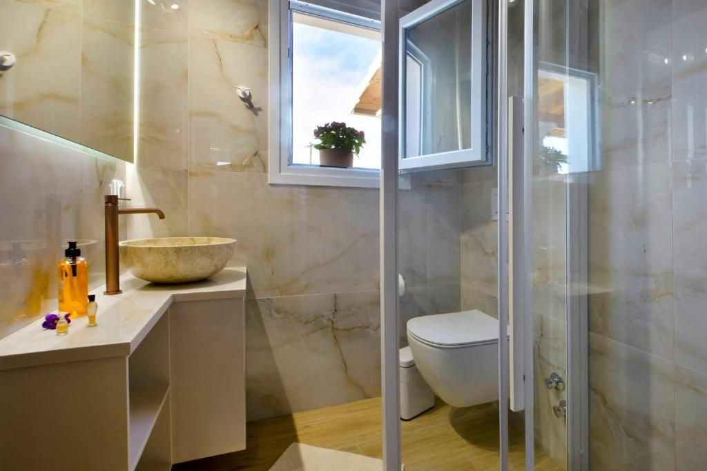 Bathroom with marble-effect tiles, stone basin and glass shower